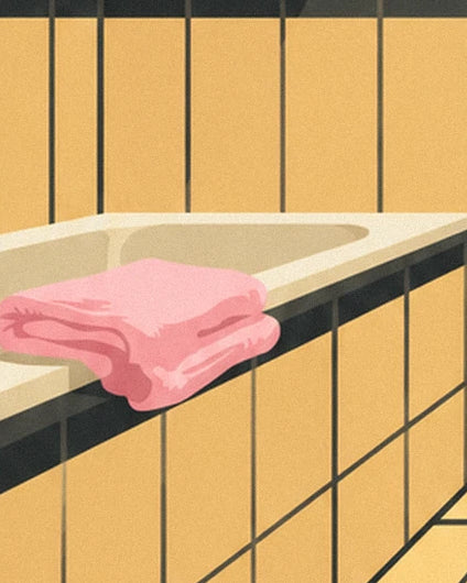 Pink towels folded on the edge of a bath with yellow tiling