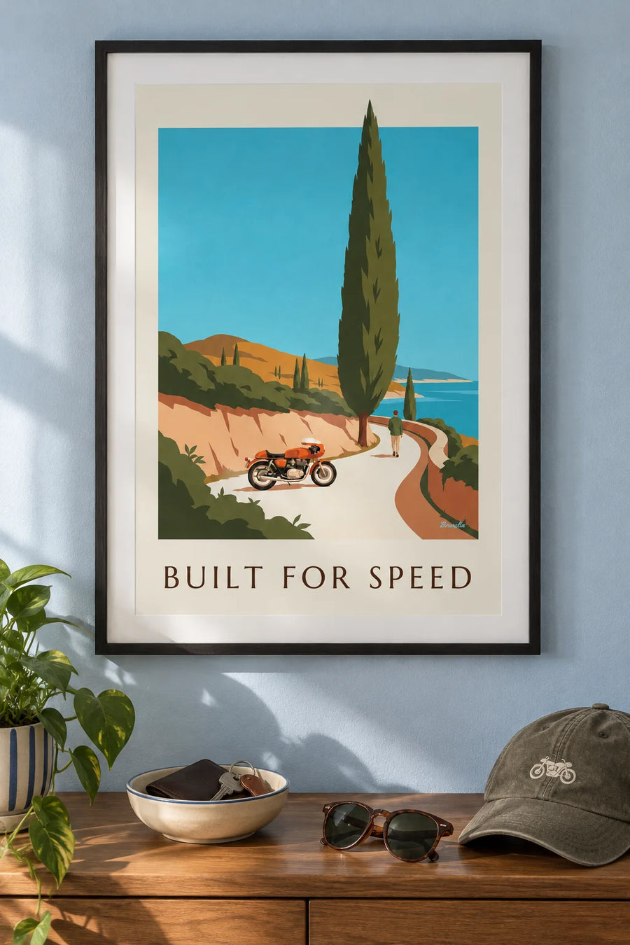 Affiche moto café racer orange sur une route côtière : encadrée au mur