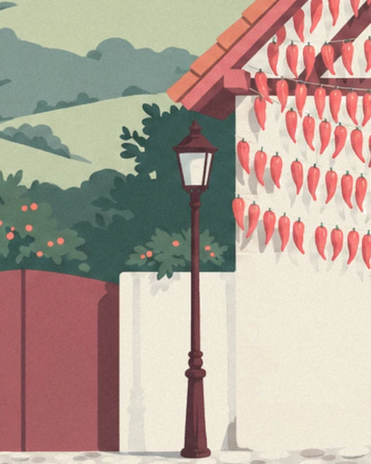 Le lampadaire en fonte devant la façade couverte de piments rouges, collines vertes au fond