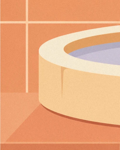 The rounded rim of a cream basin filled with lilac water, resting on terracotta tiles
