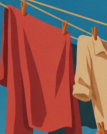 Un drap rouge et une chemise crème suspendus aux cordes par des pinces en bois