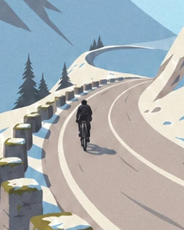 A cyclist on the winding mountain pass road, lined with snow and stone markers