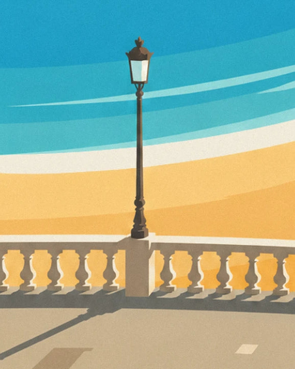 Le réverbère en fer noir et la balustrade en pierre dorée, face à la plage et au ciel bleu