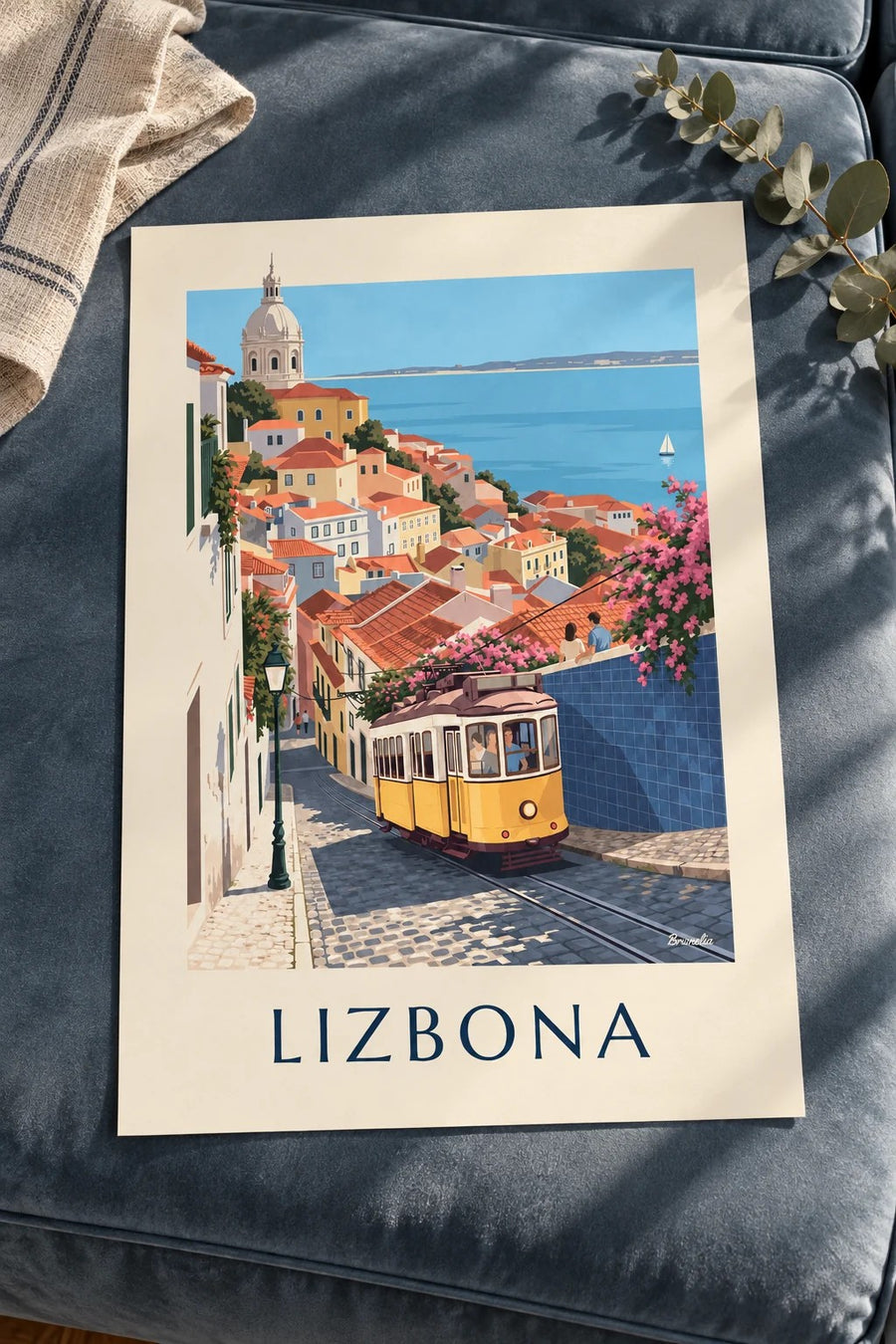 Plakat żółty tramwaj na brukowanej uliczce Lizbony z widokiem na Tag: leżący na stole