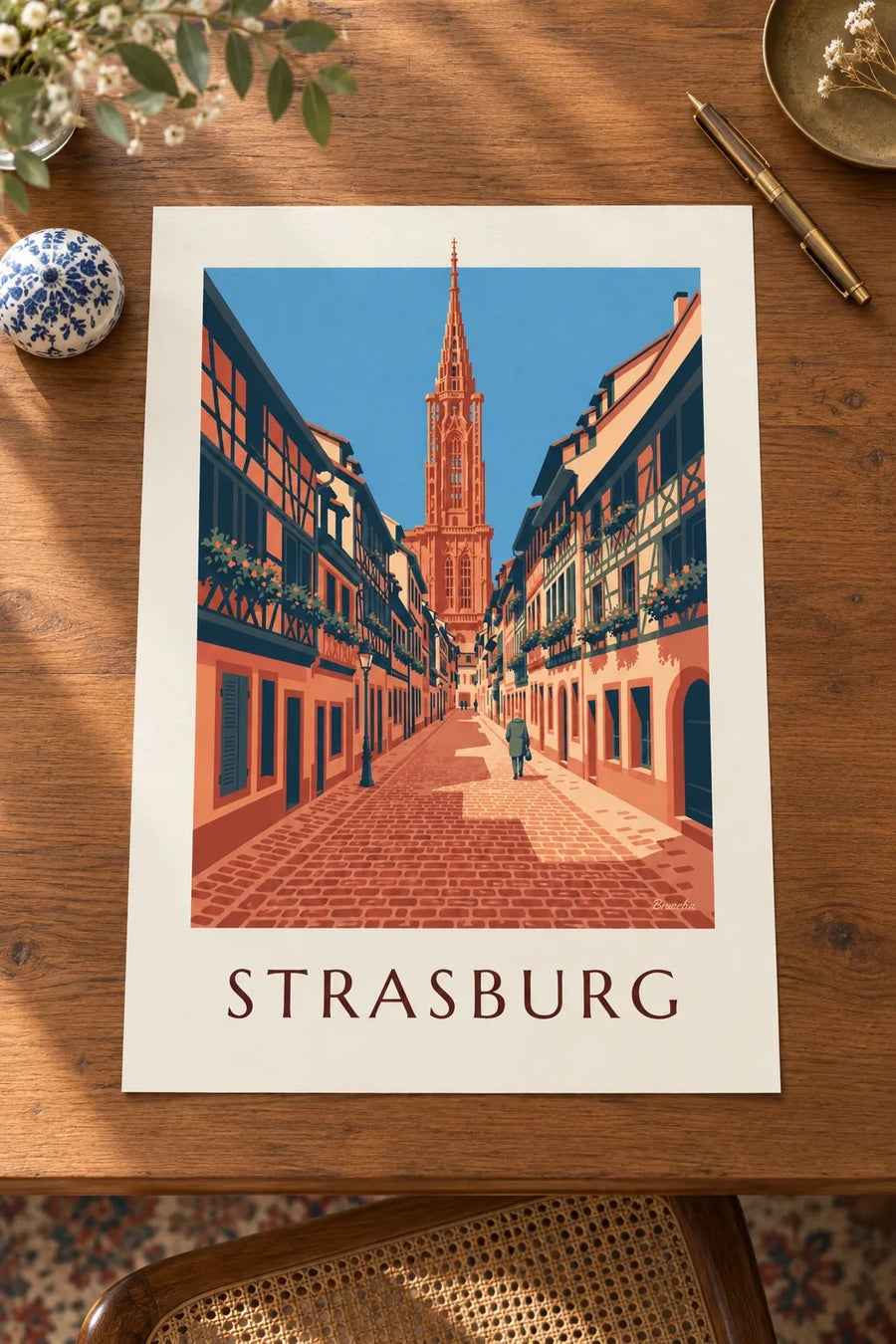 Plakat z brukowaną uliczką i katedrą w starym Strasburgu: oparty na stole